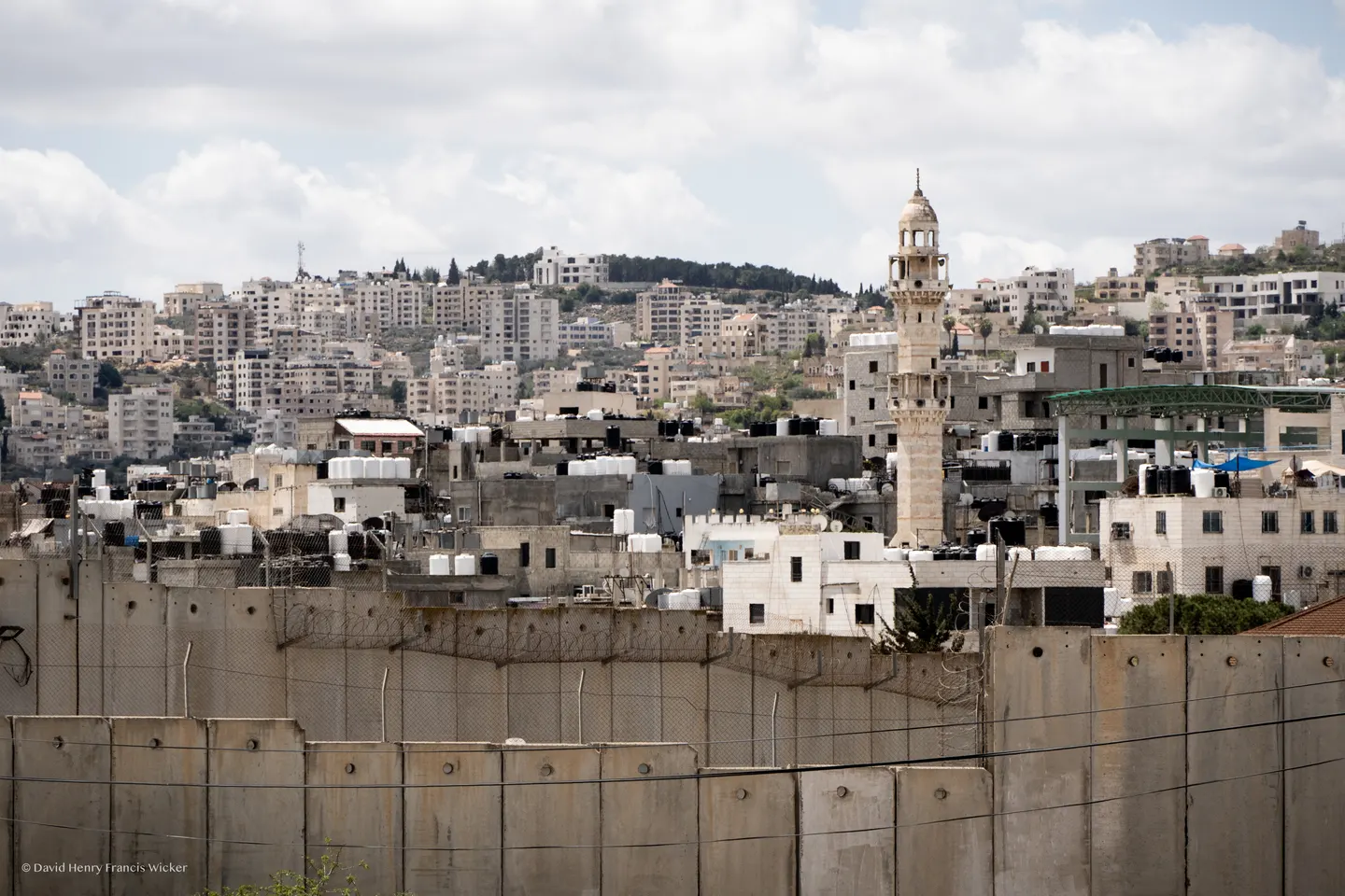 Bethlehem rises behind the concrete separation wall, with dense buildings extending across the hillside.